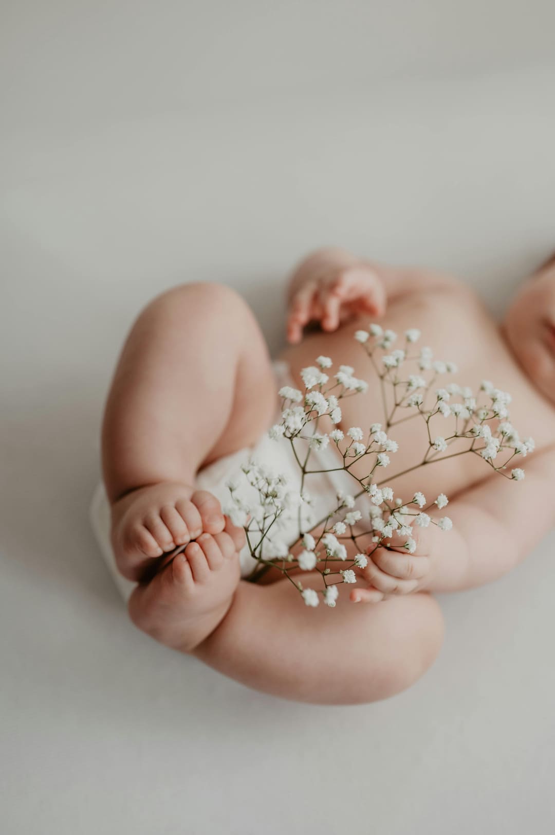 Baby in Rückenlage hält Blumen