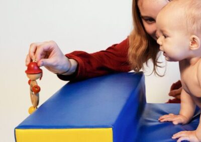 Mutter zeigt Baby auf Polster ein Spielzeug