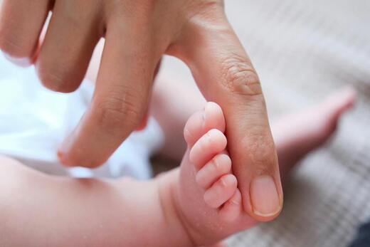 Babyfuß und Männerhand klein